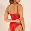 Woman wearing a red lace lingerie set against a beige background
