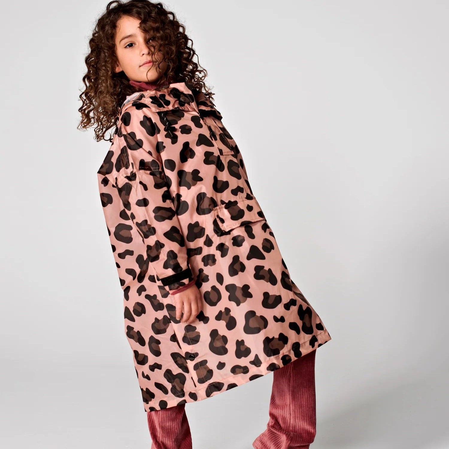 Person wearing a pink leopard print coat on a white background