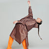 Person wearing a long, striped coat over orange pants on a plain background