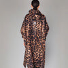 Person wearing a leopard print coat on a plain background